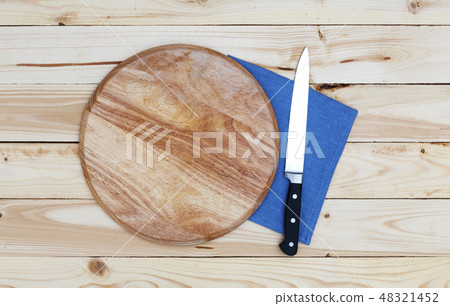Round cutting board with a knife on a wooden table, top view Round cutting board with a knife on a wooden table, top view 48321452