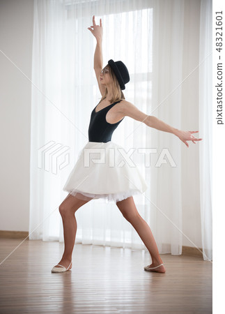 Ballerina in the hat is dancing raising hands, in the studio 48321601