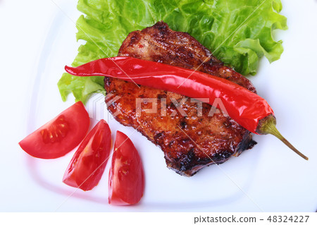 Beef steak on barbeque and chili pepper with tomato, lettuce leaves on white plate 48324227