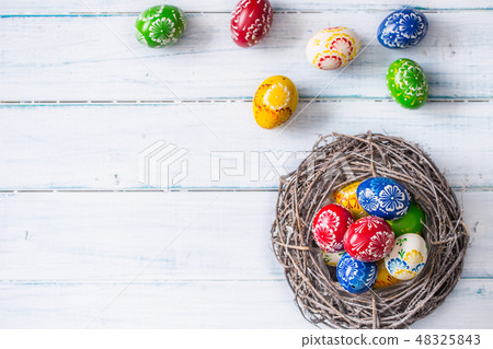 Multicolored easter eggs in basket on wooden table Multicolored easter eggs in basket on wooden table 48325843
