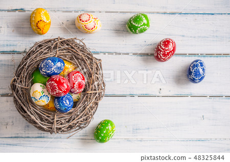 Multicolored easter eggs in basket on wooden table Multicolored easter eggs in basket on wooden table 48325844