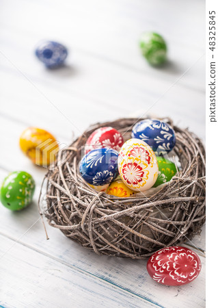 Multicolored easter eggs in basket on wooden table 48325845