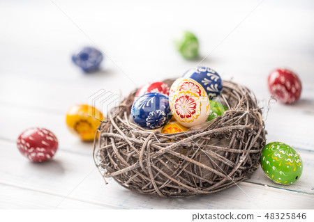 Multicolored easter eggs in basket on wooden table Multicolored easter eggs in basket on wooden table 48325846