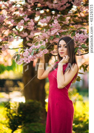 Beautiful girl posing to the photographer against the background of blooming pink trees. Spring Beautiful girl posing to the photographer against the background of blooming pink trees. Spring 48326555