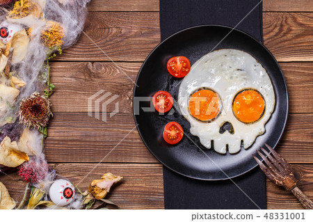 Fried eggs in the shape of a skull and fresh tomatoes. Breakfast in Halloween decorations. Fried eggs in the shape of a skull and fresh tomatoes. Breakfast in Halloween decorations. 48331001