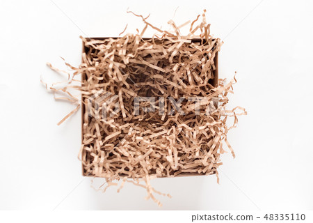 Opened gift box with decorative straws fillers on light background. Brown craft paper box for your 48335110