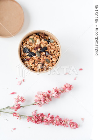 Home made granola cereal flakes with dried fruit, nuts and honey in a craft paper box with dried Home made granola cereal flakes with dried fruit, nuts and honey in a craft paper box with dried 48335149