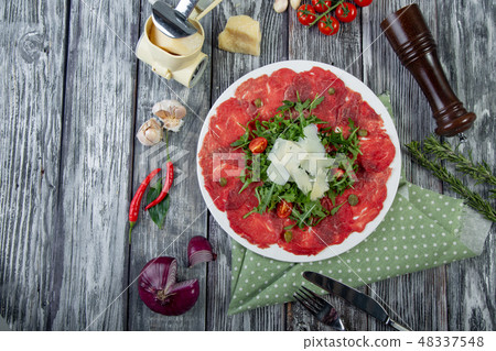 close-up carpaccio meat with arugula and slices of parmesan cheese close-up carpaccio meat with arugula and slices of parmesan cheese 48337548