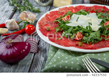 close-up carpaccio meat with arugula and slices of parmesan cheese 48337550