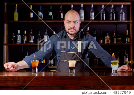 Fiery show at the bar. The bartender makes hot alcoholic cocktail and ignites bar. Bartender 48337949