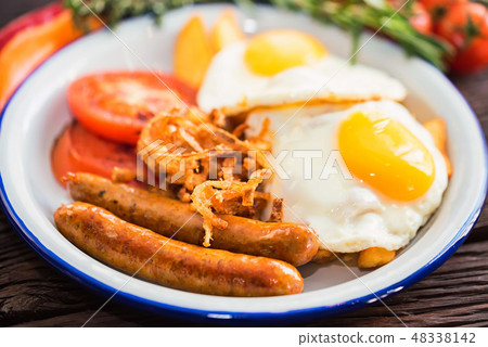 Typial breakfast with eggs, tomato, onion rings and sausage on plate Typial breakfast with eggs, tomato, onion rings and sausage on plate 48338142
