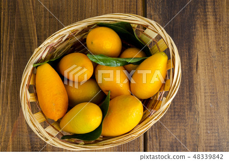 Ripe sweet orange kumquats fortunella in wooden Ripe sweet orange kumquats fortunella in wooden 48339842