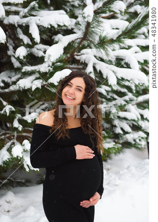 Young happy pregnant woman in snowy forest 48341980