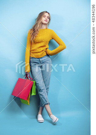 young pretty woman posing emotional on blue background with bags, lifestyle people concept 48344196