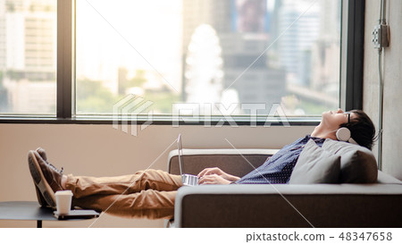 Asian man lying down on comfortable sofa Asian man lying down on comfortable sofa 48347658
