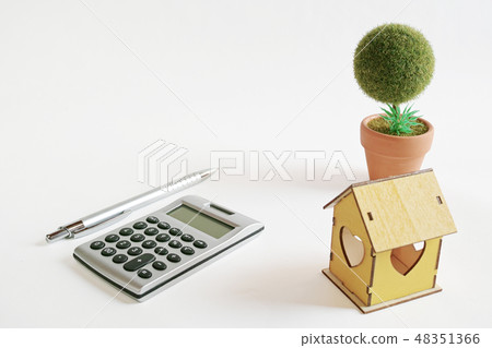 白皮書，計算器，圓珠筆和創作圓的盆的樹的黃色木房子 48351366