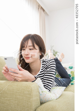 A woman using a smartphone on a sofa A woman using a smartphone on a sofa 48352705