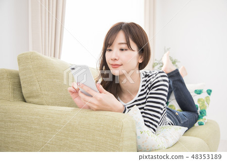 A woman using a smartphone on a sofa 48353189
