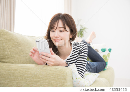 A woman using a smartphone on a sofa A woman using a smartphone on a sofa 48353433