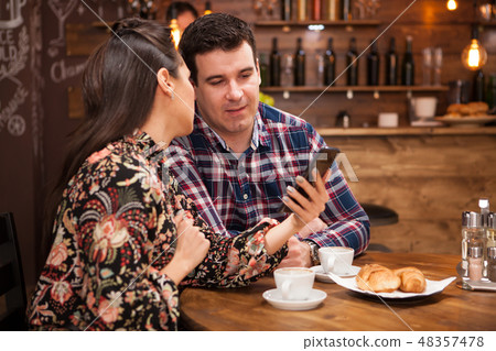 Beautiful wife and husband look at the phone while having dinner. Beautiful wife and husband look at the phone while having dinner. 48357478