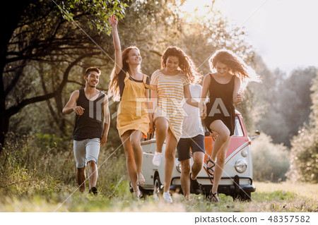 A group of young friends on a roadtrip through countryside, jumping. A group of young friends on a roadtrip through countryside, jumping. 48357582
