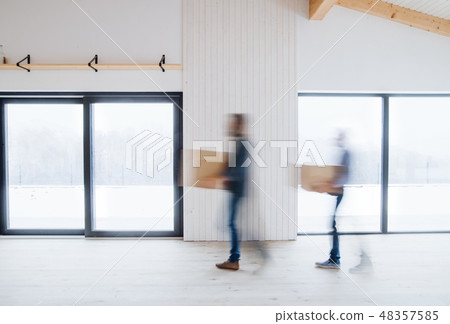 Two men walking with cardboard boxes when furnishing new house. Motion blur. 48357585