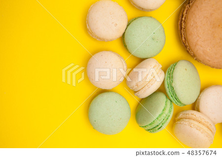 Top view of big caramel macaroon flavour next to little macaroons over yellow background 48357674
