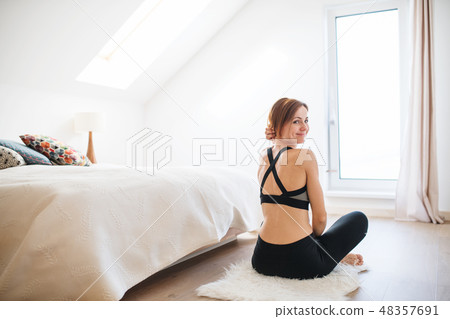 A young woman doing yoga exercise indoors in a bedroom. Copy space. A young woman doing yoga exercise indoors in a bedroom. Copy space. 48357691