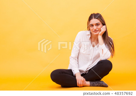 Beautiful young girl in white shirt smilling in studio over yellow background Beautiful young girl in white shirt smilling in studio over yellow background 48357692
