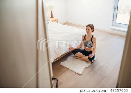 A young woman doing yoga exercise indoors in a bedroom. Copy space. 48357693