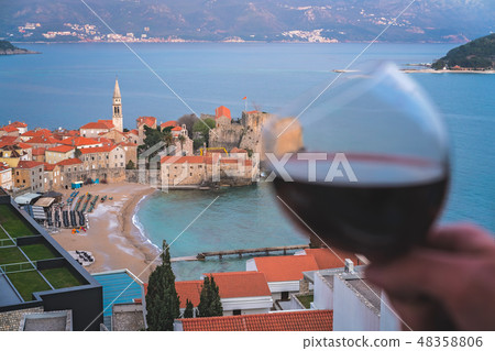 Glass with red wine above Budva 48358806