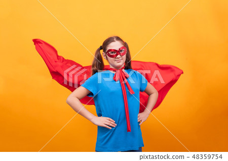 Little girl in super hero costume ready to save the world from bad guys over yellow background 48359754