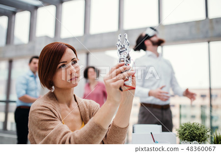 Young businesswoman or scientist with robotic hand standing in office, working. 48360067