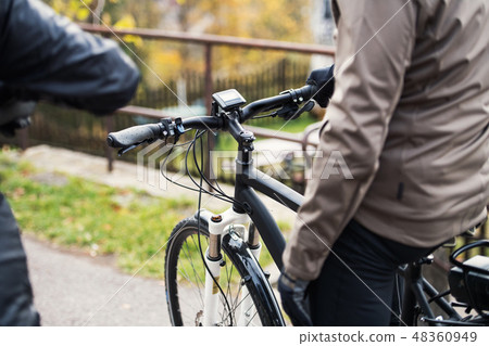 A midsection of active senior couple with electrobikes cycling outdoors. A midsection of active senior couple with electrobikes cycling outdoors. 48360949