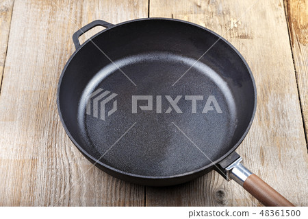 a cast-iron frying pan on a wooden background 48361500