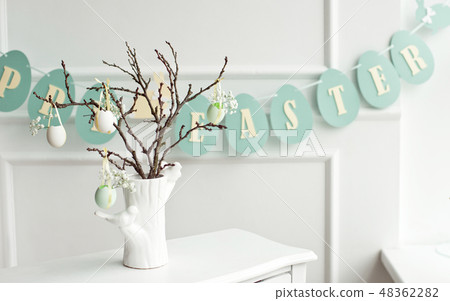Decoration of the Easter table, a vase with a branch and decorations from flowers and eggs, biscuits 48362282