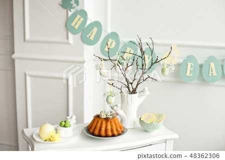 Decoration of the Easter table, a vase with a branch and decorations from flowers and eggs, biscuits 48362306