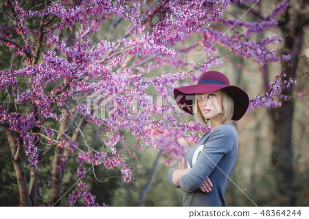 Young woman smiling on the red garden background, copy space 48364244