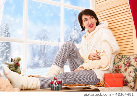 Woman sitting on window sill - sunny day in winter Woman sitting on window sill - sunny day in winter 48364491