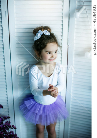 Adorable little girl dressed as a ballerina in a tutu, tying her ballet slippers. 48364935