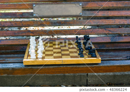 Old chess on wooden bench in city park Old chess on wooden bench in city park 48366224