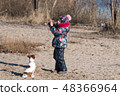 little girl in hat and jacket in the winter plays  48366964