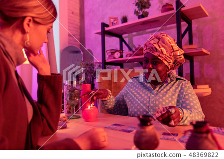 African american plump fortune-teller with a huge ring pointing to a cup African american plump fortune-teller with a huge ring pointing to a cup 48369822