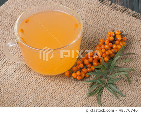 Sea buckthorn tea with a sprig on sackcloth Sea buckthorn tea with a sprig on sackcloth 48370740