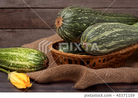 green zucchini or courgettes with a flower on sackcloth wooden background 48371189