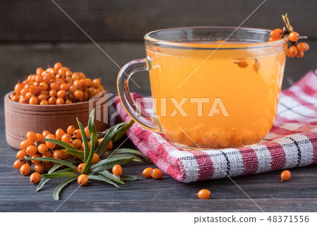 Tea of sea-buckthorn berries with branch on dark wooden background 48371556