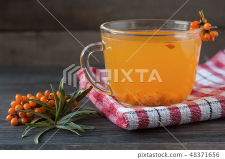 Tea of sea-buckthorn berries with branch on dark wooden background 48371656