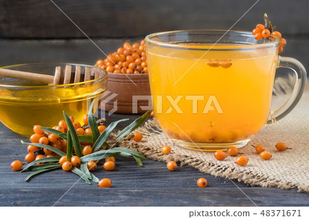 Tea of sea-buckthorn berries with a sprig on sackcloth and wooden background 48371671