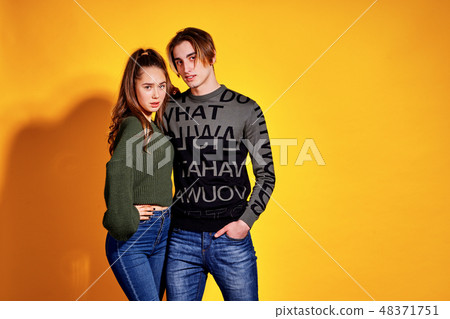 Couple posing in jeans type commercial fashion style on yellow wall Couple posing in jeans type commercial fashion style on yellow wall 48371751