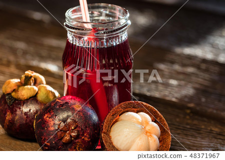 Fresh Mangosteen fruit and drink in jar on wooden background Fresh Mangosteen fruit and drink in jar on wooden background 48371967